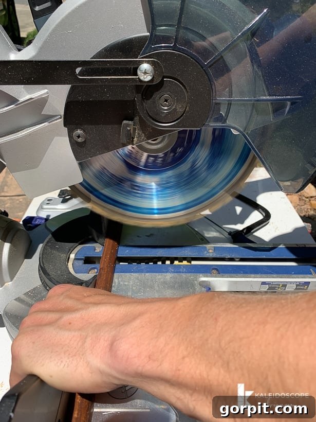 Your Guide to Perfect Quarter-Round Molding 4 A man is cutting quarter round molding trim with a compound miter saw. The corner text reads, "KaleidoscopeLiving.com." He is preparing the molding for installation.