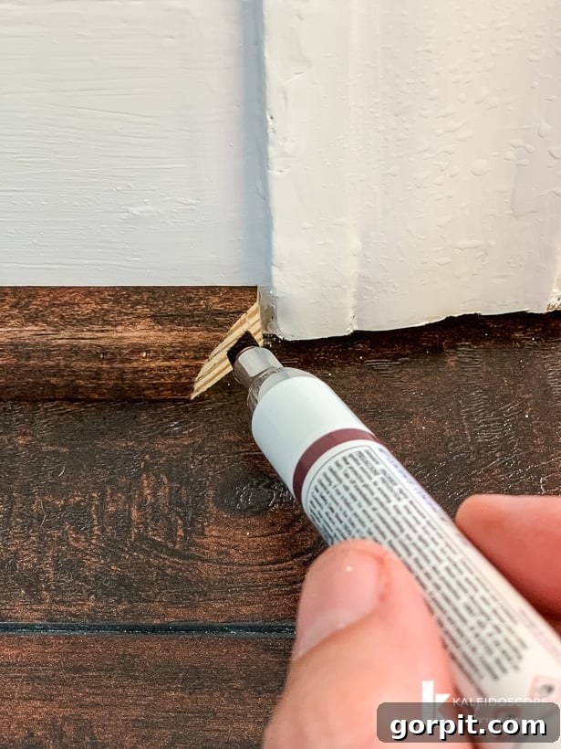 Your Guide to Perfect Quarter-Round Molding 8 A Mohawk Pro-Mark marker is being used to color the end of quarter round molding installed on a white wall, ensuring a seamless finish. The text reads, "KaleidoscopeLiving.com."