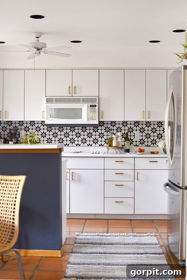 A dark blue and white kitchen features a geometric wallpaper backsplash. 