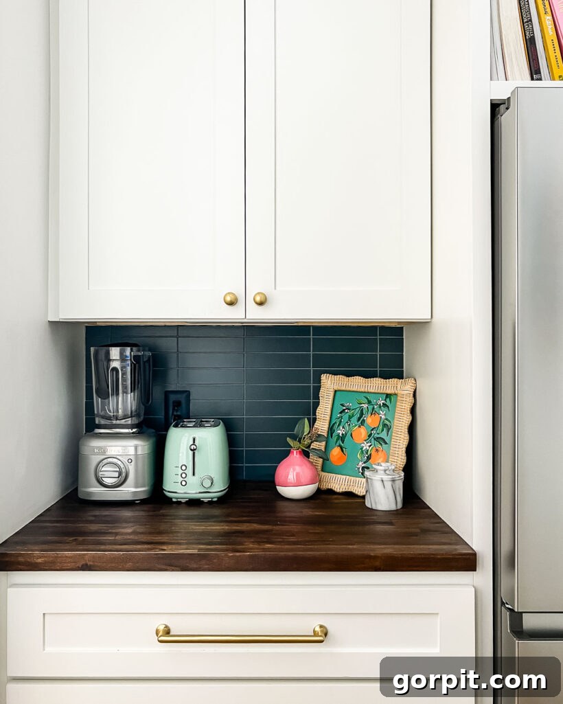A dark tile backsplash pops against white cupboards with gold hardware. 