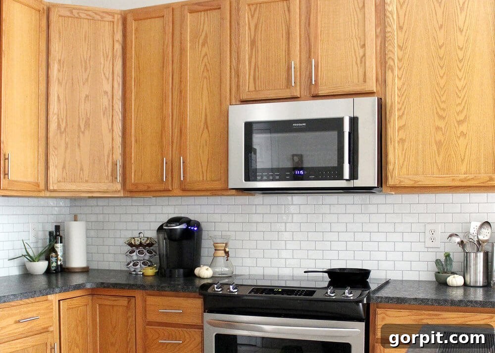 A simple peel-and-stick subway tile backsplash instantly elevates and modernizes brown cupboards in this kitchen update. 