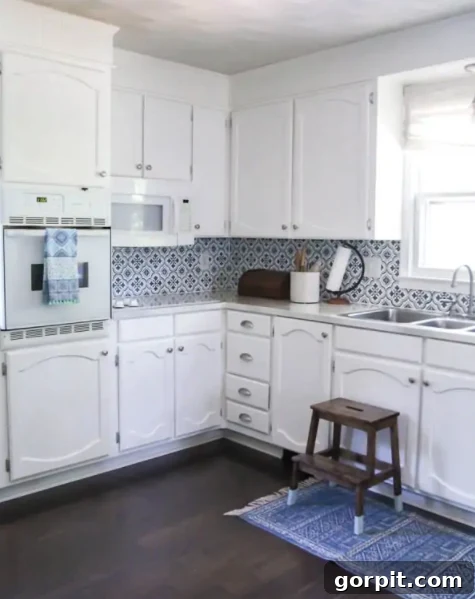 A charming blue and white kitchen gets a pop of color from a painted backsplash that looks like tile. 