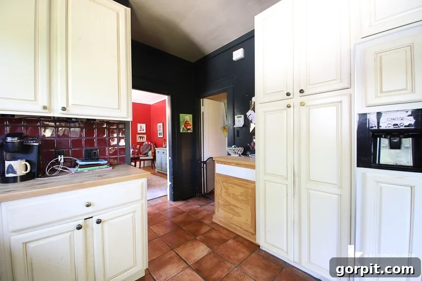 Small Budget Big Impact DIY Kitchen Transformation 5 A different view of the back half of an outdated kitchen before budget-friendly kitchen makeover shows white cabinets, dark walls, and a narrow entry.