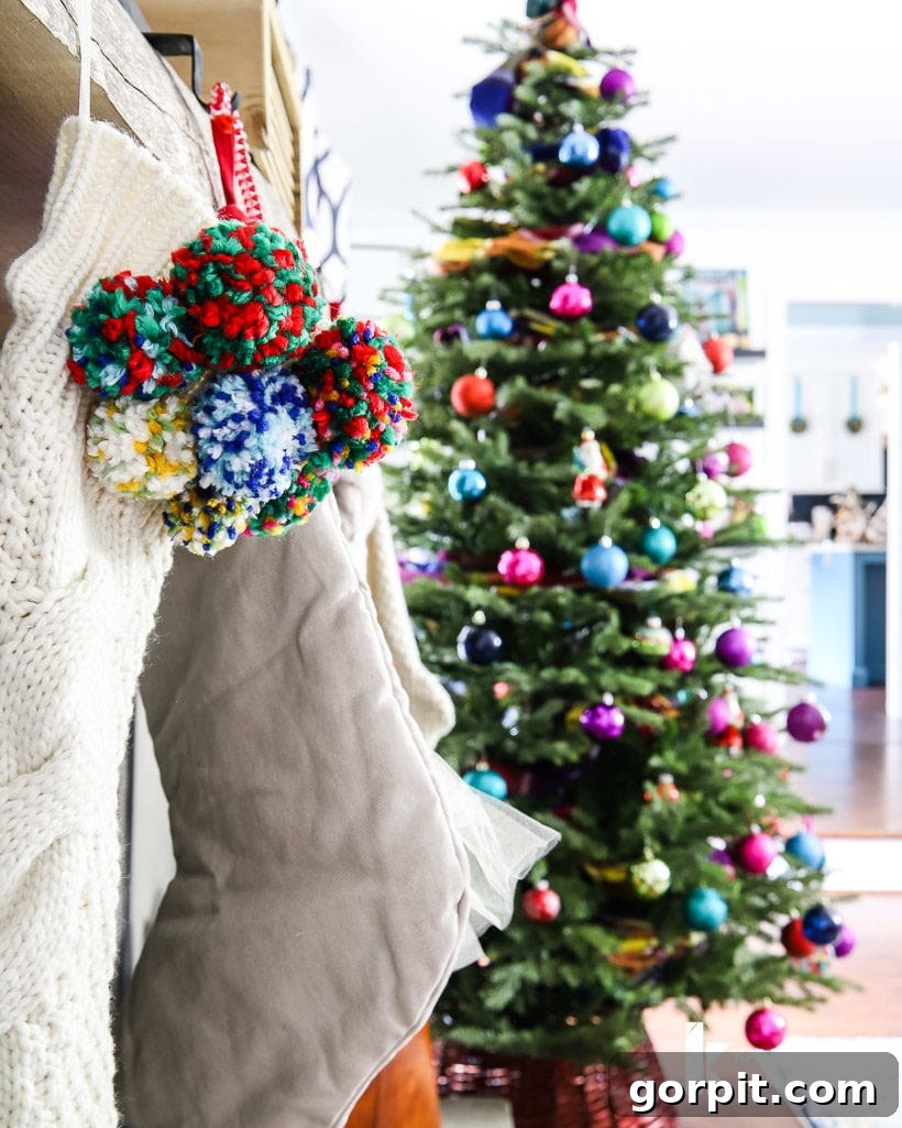 Vivacious Holiday Tree 7 A cozy pom-pom stocking hanging against a charming fireplace, with a brightly lit and colorful Christmas tree softly blurred in the background, setting a warm holiday scene