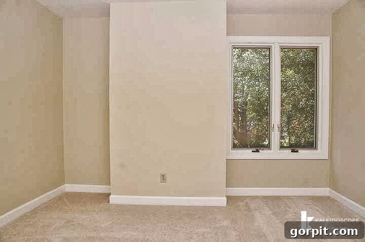 Empty, beige bedroom before makeover, highlighting a challenging layout with a chimney niche.