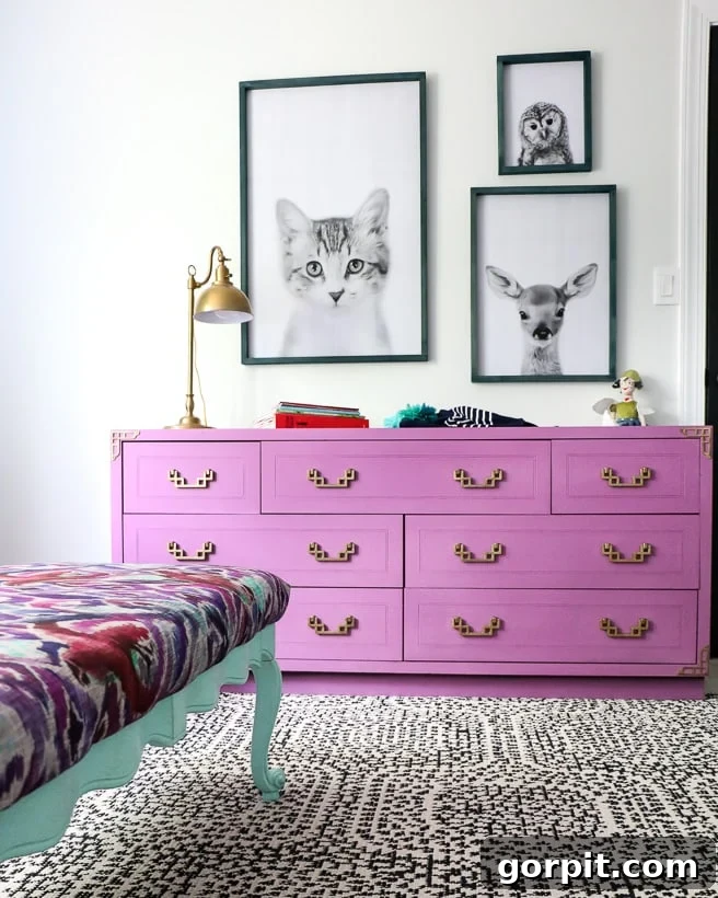 A girl's bedroom with repurposed drawers painted purple with framed animal pictures above it. 