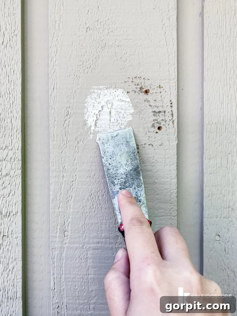 Applying exterior filler to patch holes on house siding