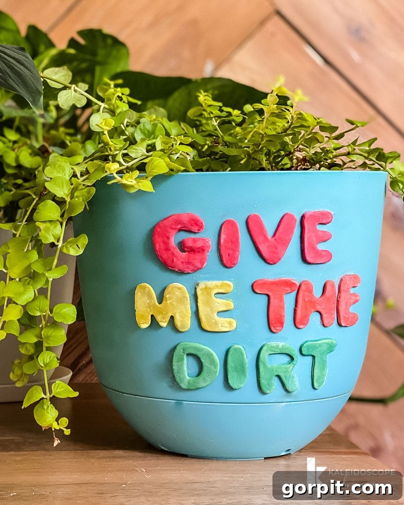 Close-up of a blue plant pot with white polymer clay shapes spelling 'PLANTS'