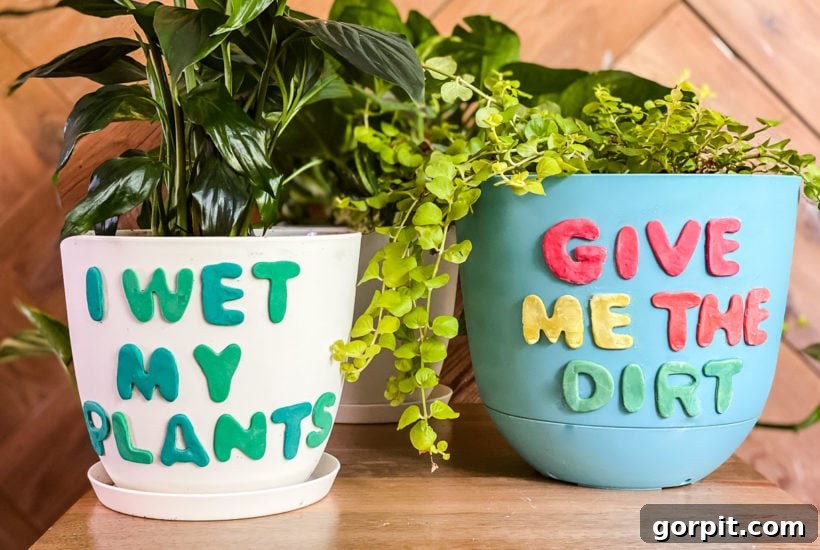 Two freshly decorated plastic plant pots with polymer clay designs