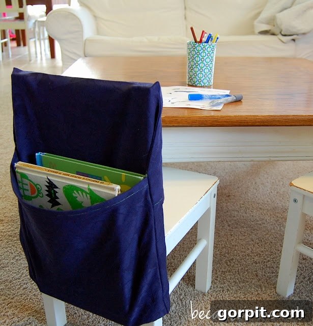 Streamline Your Homeschool: Genius Organization Strategies 7 A blue handmade schoolbook organizer hangs from the back of a white chair in front of a table, providing convenient storage for daily schoolwork.
