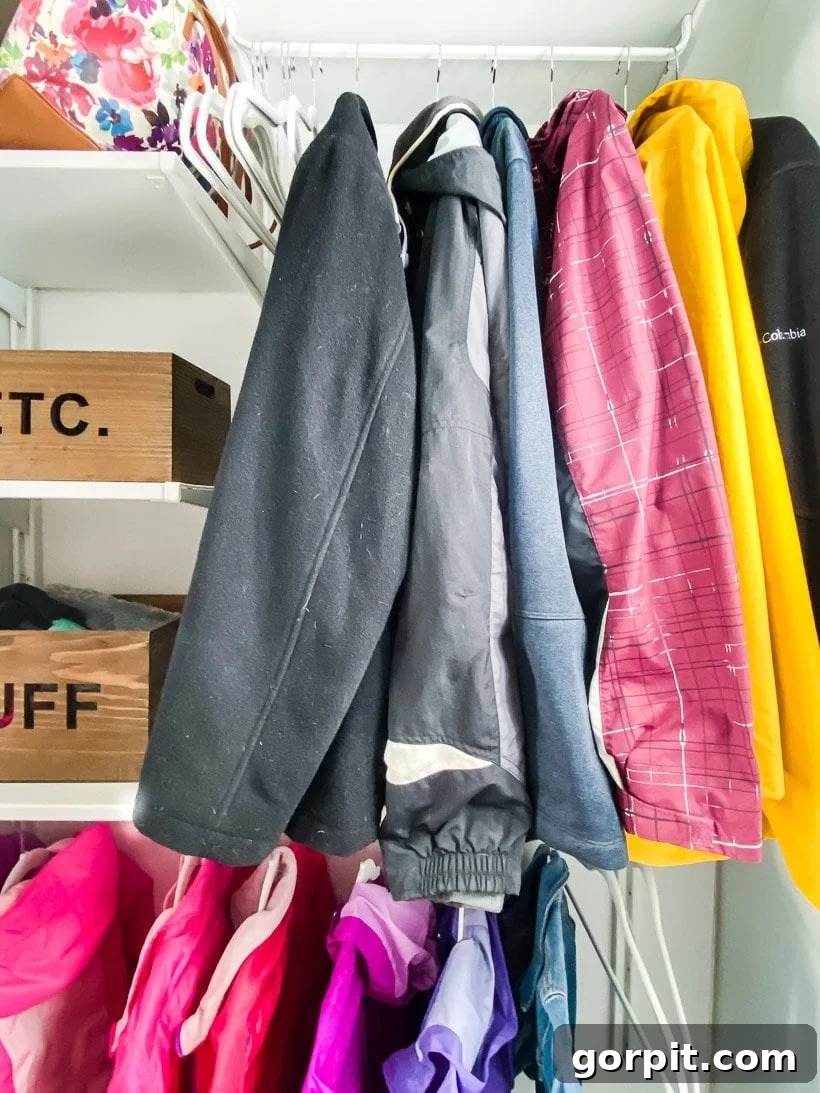 Organized coat closet with clothes neatly hung on uniform hangers and accessories in bins
