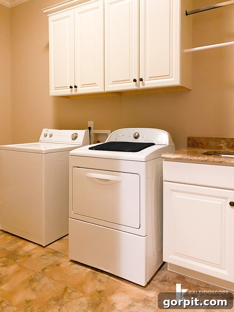Our New House: The Starting Point Tour Part 1 25 Large laundry room with basic cabinets, a sink, and a patterned floor tile.
