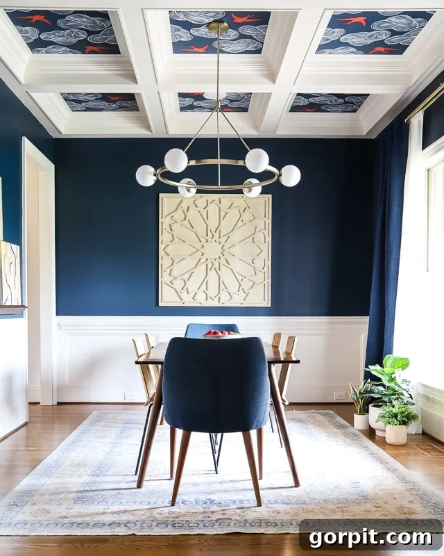 Welcome to Our Navy Dining Room 3 An "after" picture of a modern navy-blue dining room with wallpapered ceiling, blue chairs, cream #D artwork and a dining room table.