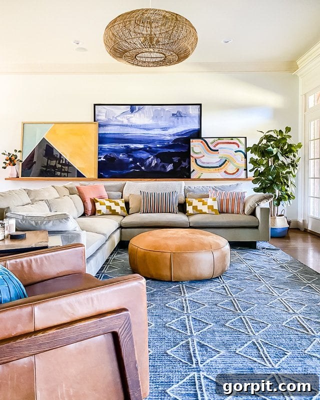 The Art of Grand Scale Elevate Your Home with Oversized Decor and Sourcing Secrets 4 An expansive living room featuring a comfortable sectional sofa and a large, colorful art collection displayed on a modern picture ledge.