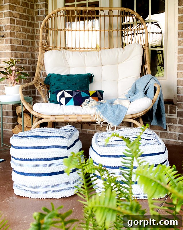 A stylish covered patio featuring a comfortable Studio McGee egg chair, complemented by colorful pillows and surrounded by lush greenery, adding vibrancy to the space.