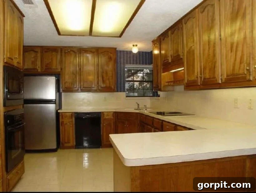 Before: Outdated kitchen with dark wood cabinets and uninspired decor, lacking brightness and modern appeal.