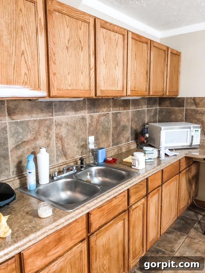 Before: Kitchen with outdated oak cabinets and brown tile backsplash, appearing dim and uninspired.