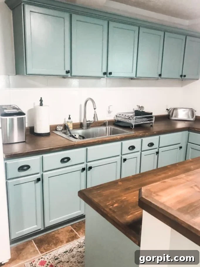 After: DIY renovated basement kitchen with painted white cabinets, new trim, a painted backsplash, and stained butcher block countertops, creating a bright and functional space.