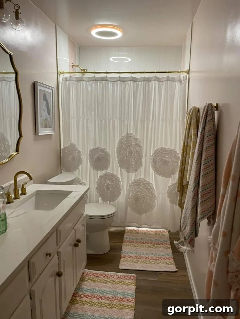 After: Beautiful pink and white girls' bathroom, featuring updated fixtures, painted details, and feminine decor, creating a charming and personalized space.