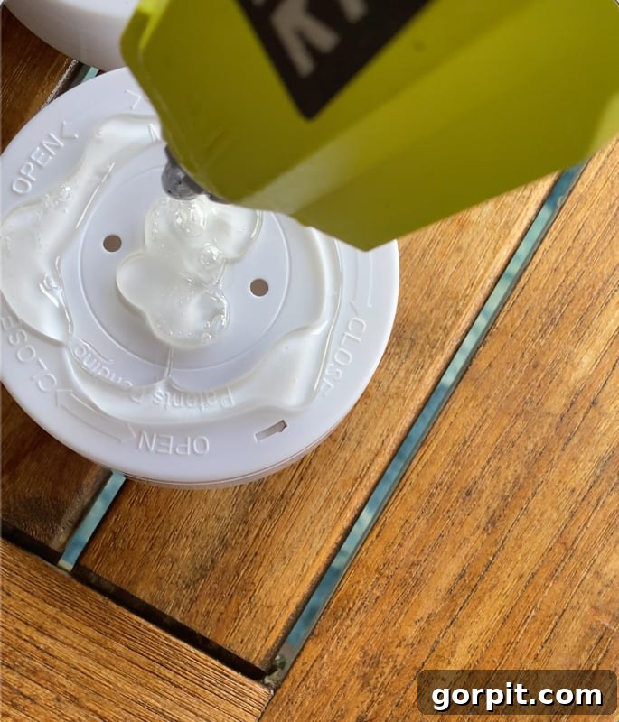 Craft Your Own Outdoor Chandelier 11 image of applying hot glue to back of puck light to glue to light shade