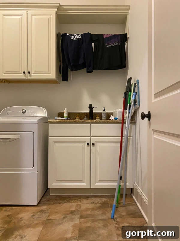 outdated laundry room before makeover - old flooring and sink area