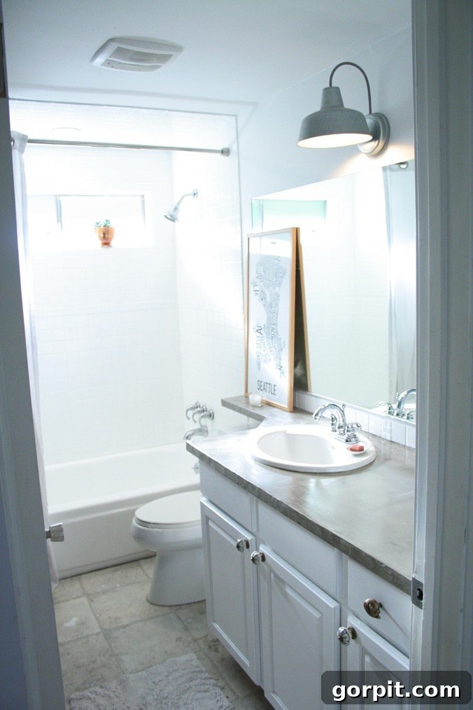 A bright, modern bathroom with shower tiles and tub after being painted white for a budget-friendly update. The space feels clean and refreshed.