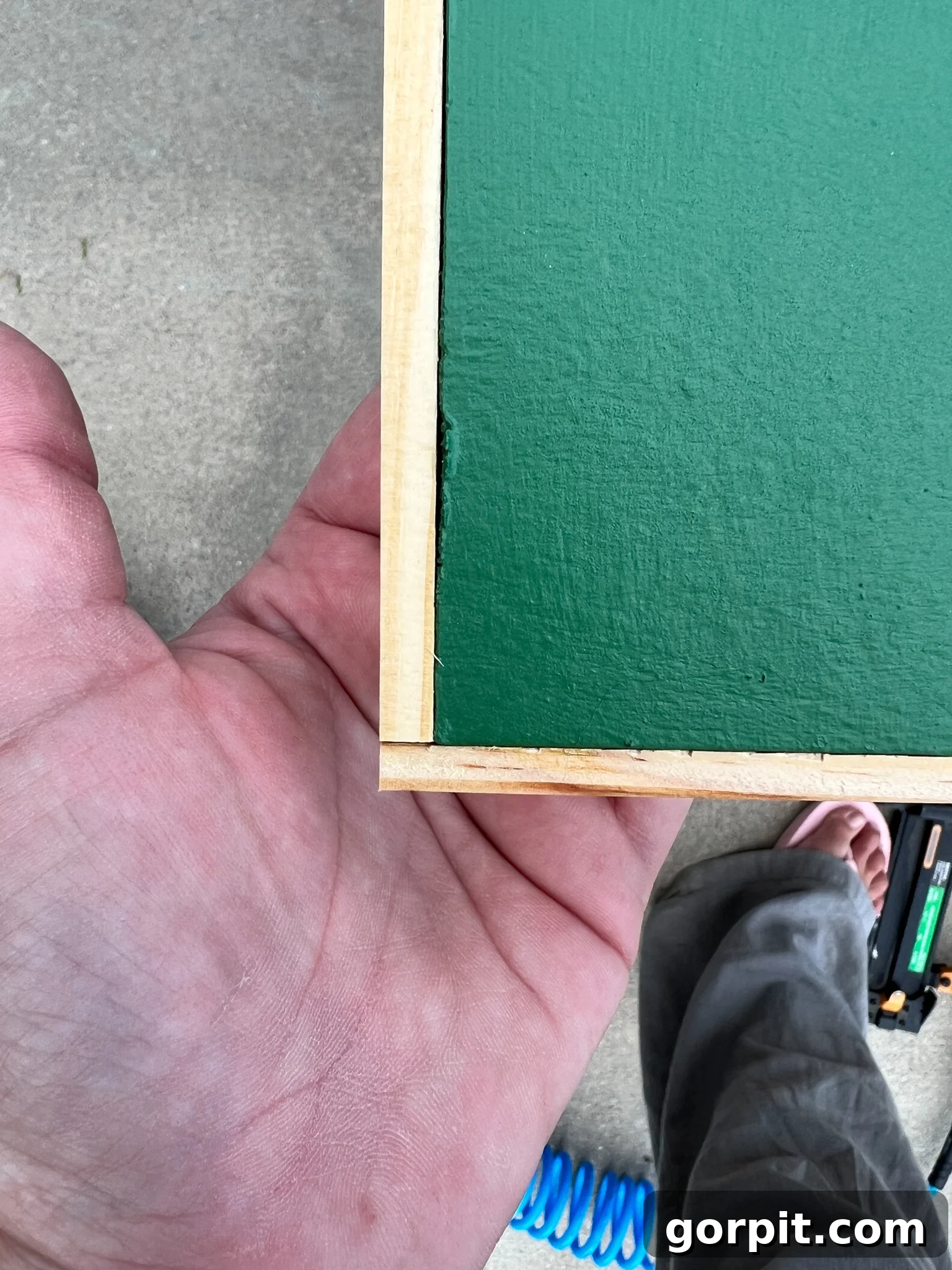 Wood lattice strips being attached to the edge of the painted plywood to form a frame.