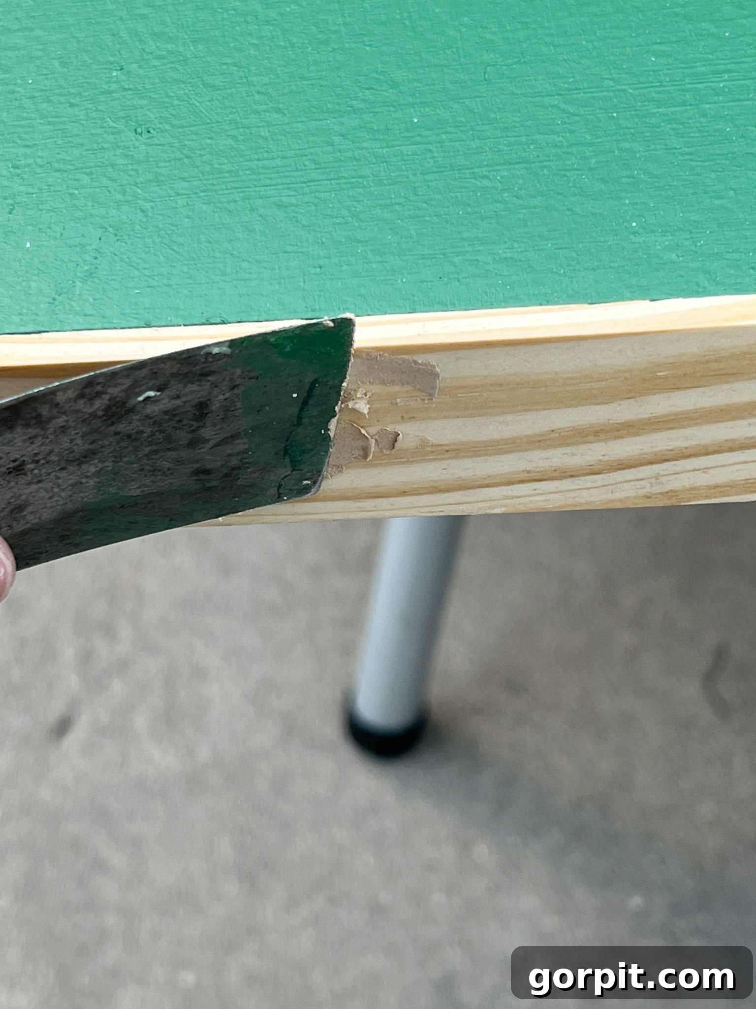 Nail holes on the wooden frame being filled with wood filler.