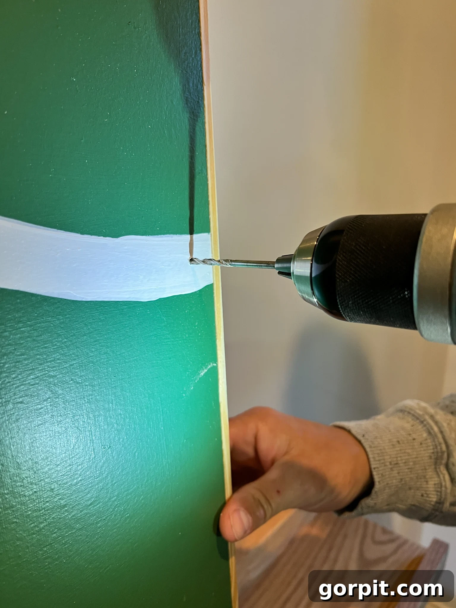 Dewdrop lights being threaded through a small hole in the plywood, with the battery pack secured at the back.