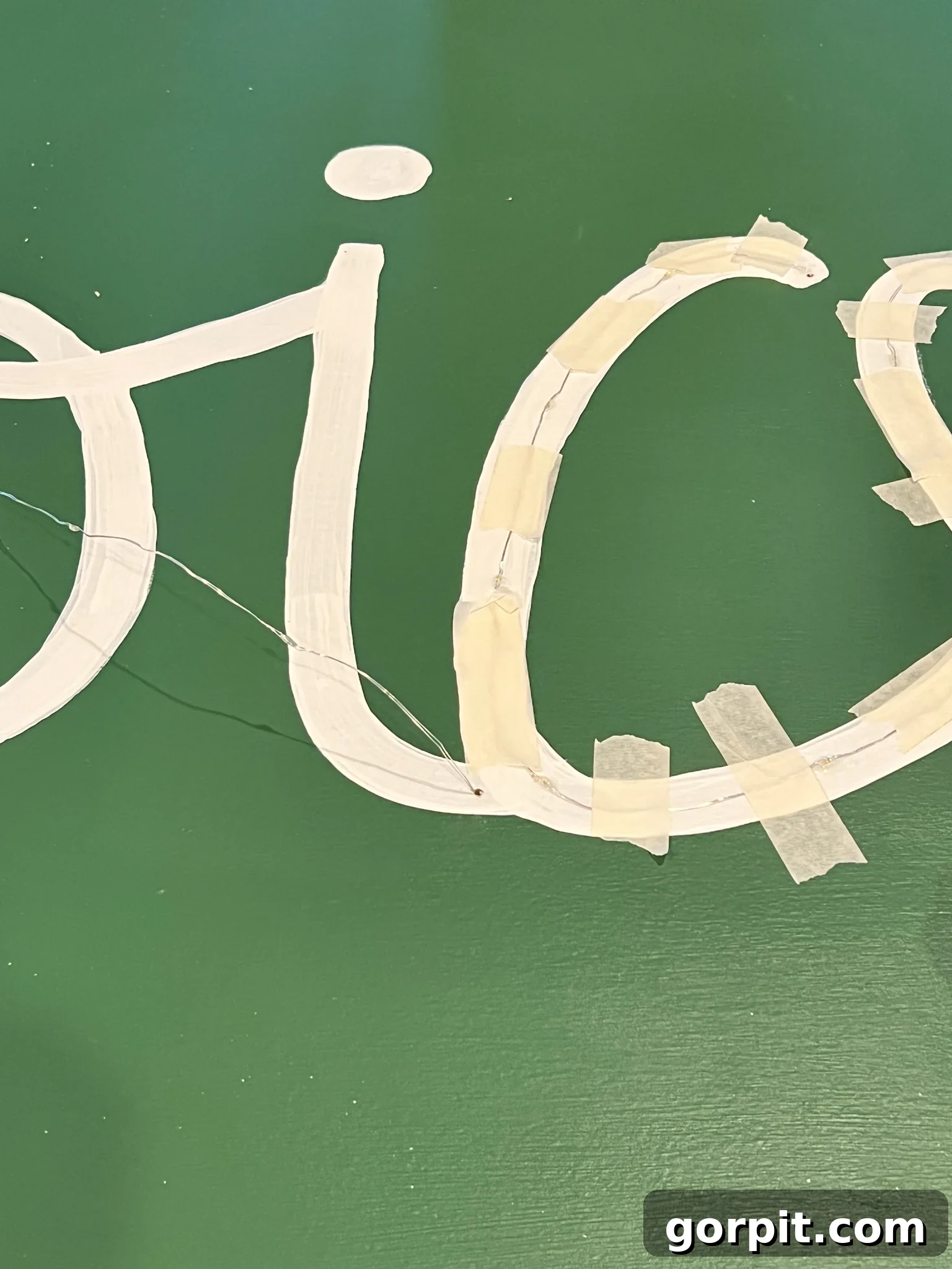 Close-up of dewdrop lights being glued and taped along the painted design on the plywood.