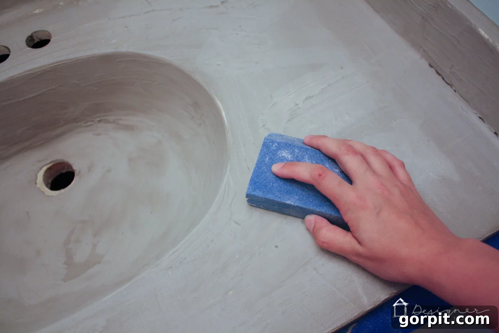 Lightly hand-sanding the first dried coat of concrete overlay