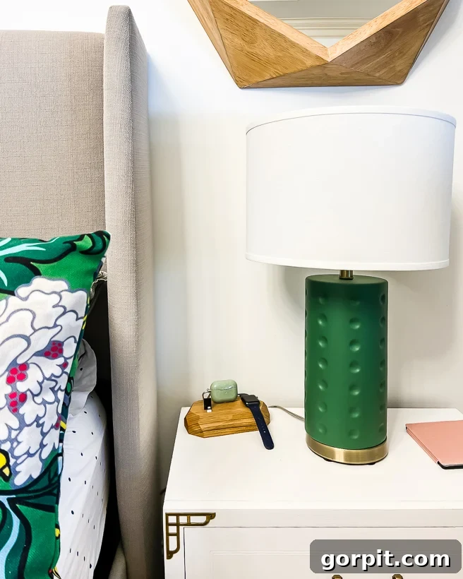 A sleek wooden block wireless personal charging station positioned on a white bedside table, accompanied by a stylish green lamp.