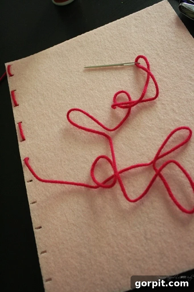 Close-up of yarn being threaded through a felt book cover with a large yarn needle, demonstrating the binding process.