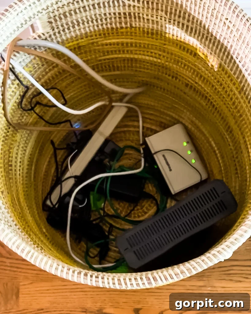 A decorative basket cleverly hiding unsightly cords and electronic devices behind a sofa in a living room.