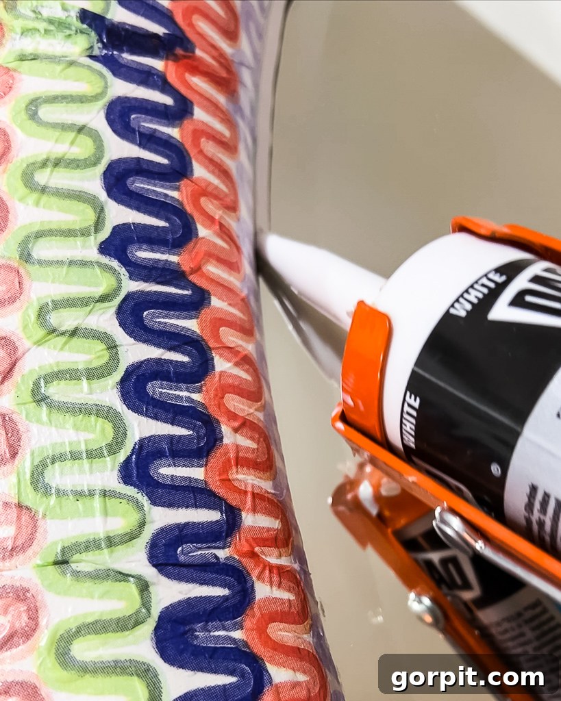 Applying caulk to seal the gap between the decoupaged frame and mirror