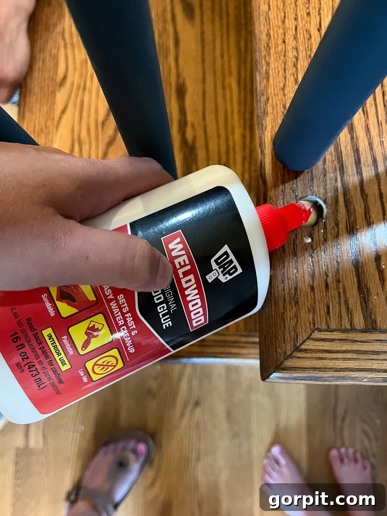 Applying wood glue to baluster pins before installation for a secure fit