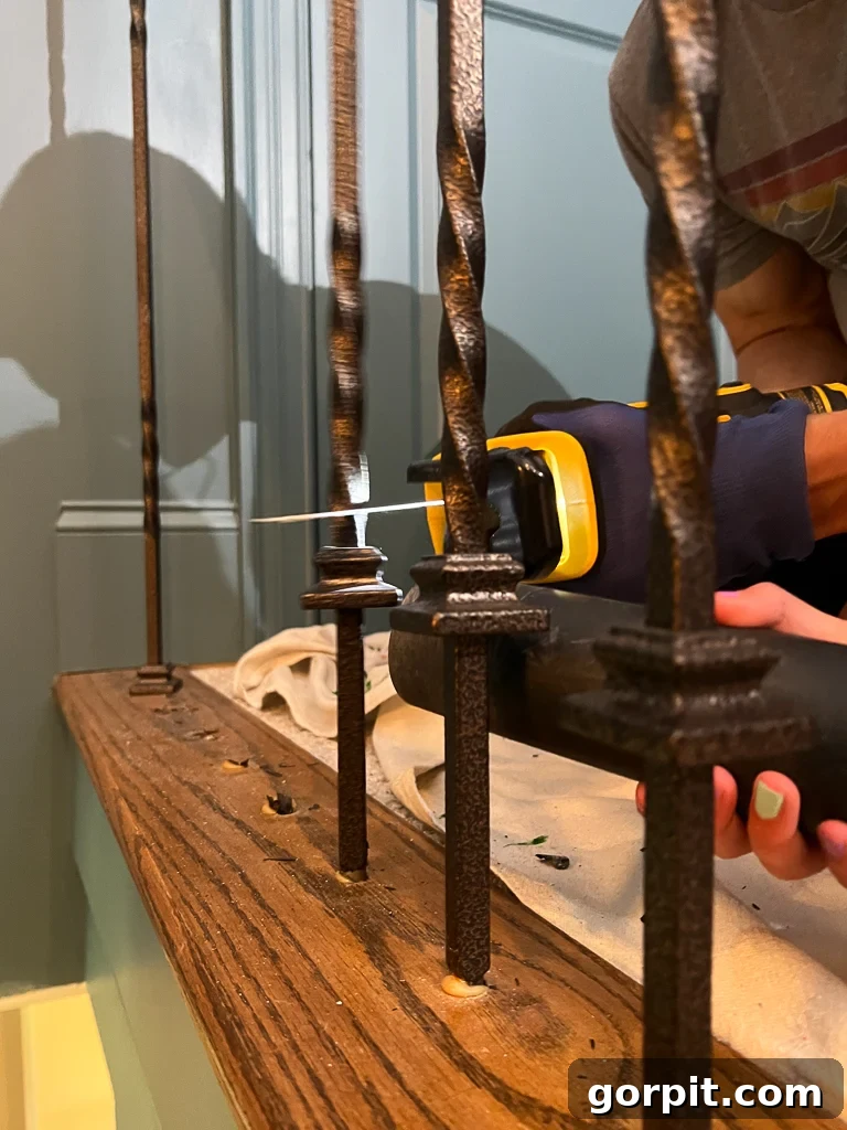 Removing old iron balusters with a reciprocating saw during stair railing renovation
