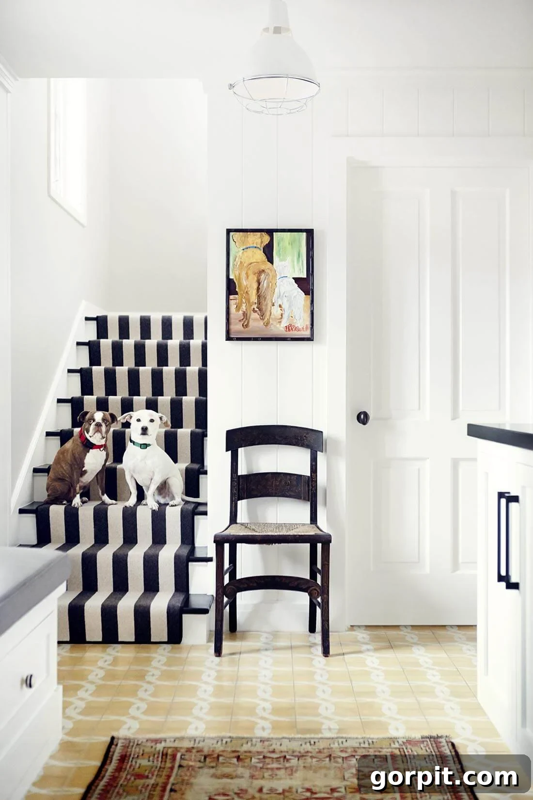 Merdivenlerinizi Şıklaştırın: İlham Veren Koşucu Halı Fikirleri 18 An indoor-outdoor black and white striped carpet on stairs that are occupied by two dogs. A black chair and white walls and cabinets are on the right.