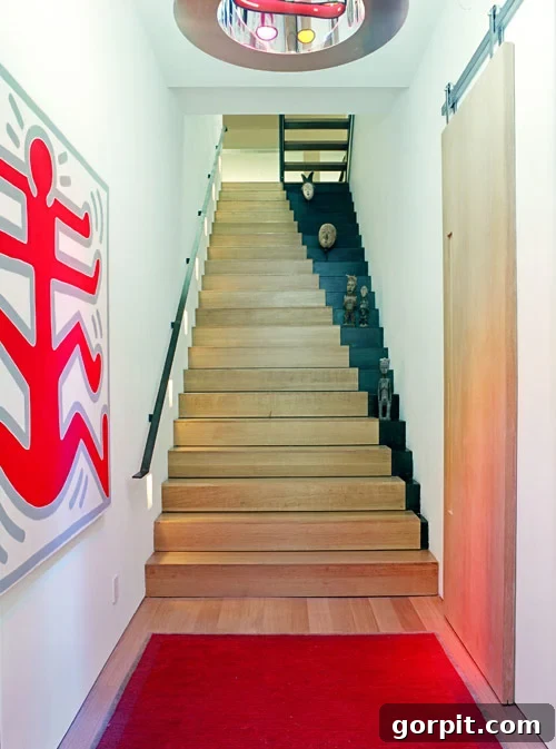 Merdivenlerinizi Şıklaştırın: İlham Veren Koşucu Halı Fikirleri 10 A wood staircase with ascending black right sides creates an illusion of the stairs getting smaller near the top. Large graphic art hangs nearby.