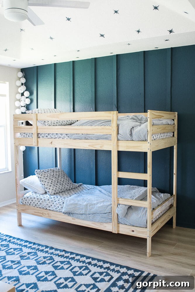 Transform Your Walls with DIY Board and Batten 19 Twin bunk beds crafted from cedar are beautifully complemented by a deep blue accent wall featuring full board and batten, and a stenciled ceiling adorned with stars, creating a whimsical and stylish children's room.