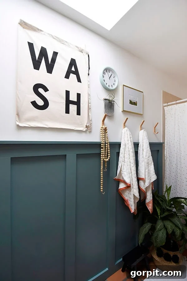 Transform Your Walls with DIY Board and Batten 20 A modern bathroom boasts a chic transformation with dark teal board and batten, perfectly harmonizing with graphic art and elegant gold towel hooks, creating a sophisticated and contemporary space.