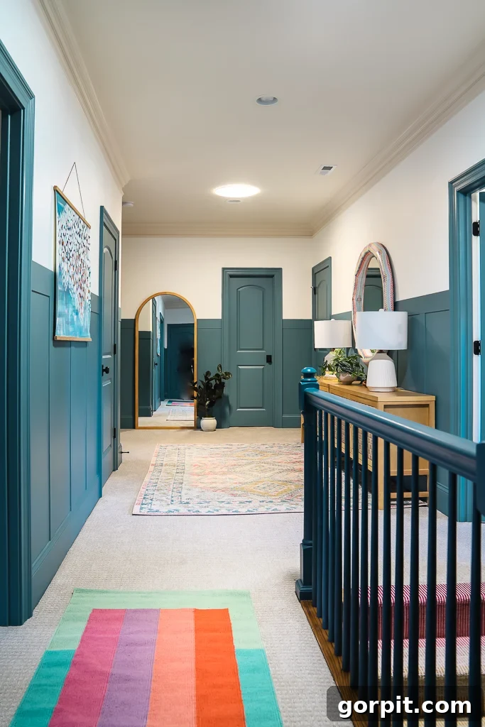 Transform Your Walls with DIY Board and Batten 3 A vibrant hallway features a colorful rug and a striking dark teal blue board and batten wall against a warm white backdrop, creating a welcoming and stylish entry.
