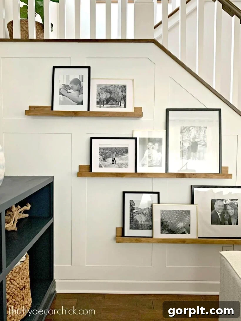 Transform Your Walls with DIY Board and Batten 6 A stylish board and batten wall, adorned with photo ledges, creates a charming portrait gallery alongside a modern staircase, blending functionality with aesthetic appeal.