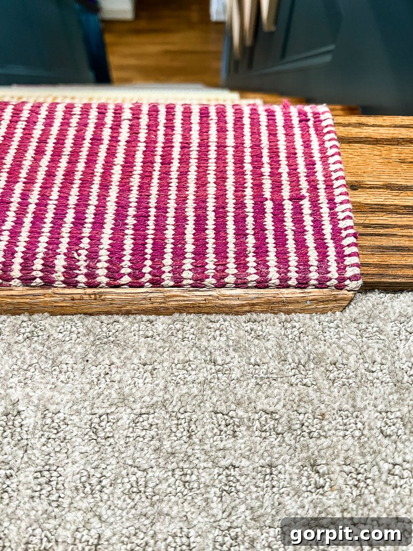 Oak quarter-round molding installed as a transition piece between the top of the stair runner and the upstairs carpet