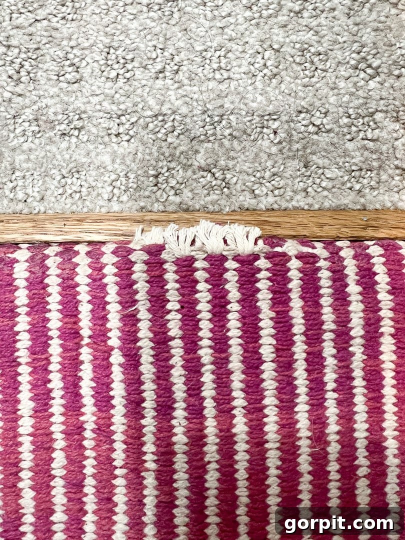 Close-up of slight fraying at the top edge of a DIY stair runner where it meets the carpet