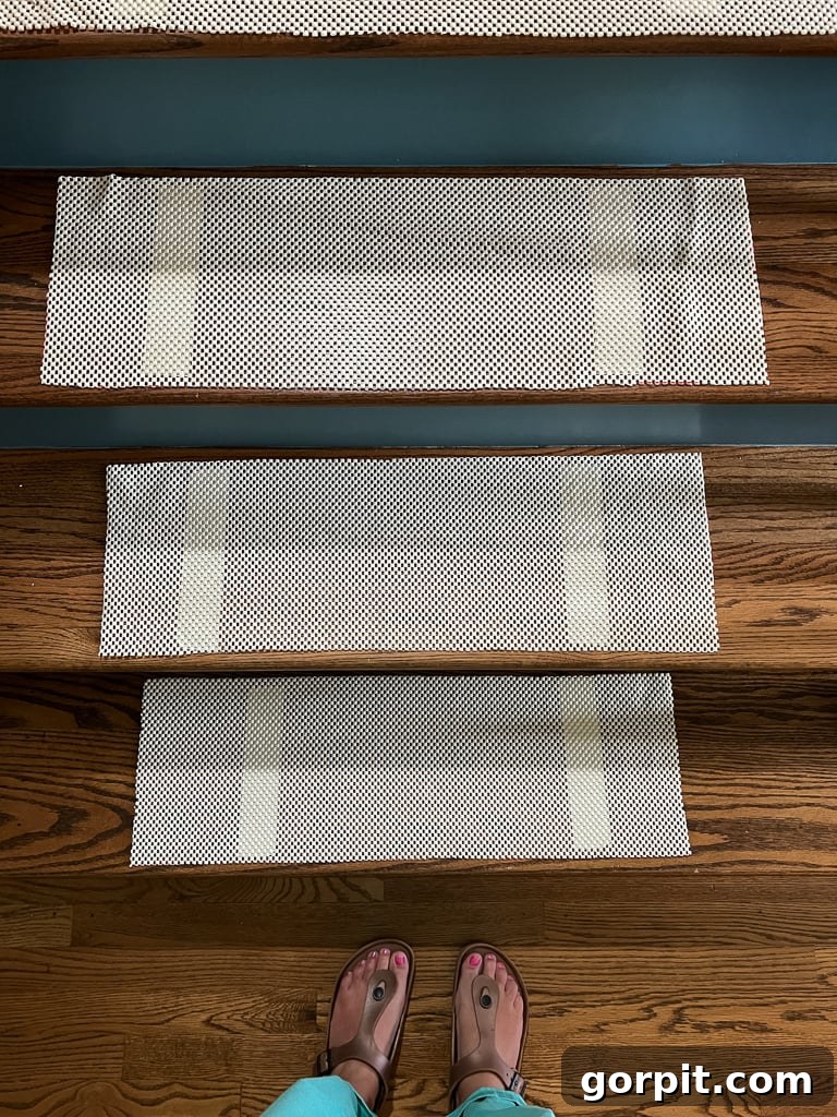 Close-up of a stair tread with a honeycomb pattern non-slip rug pad securely taped in the center