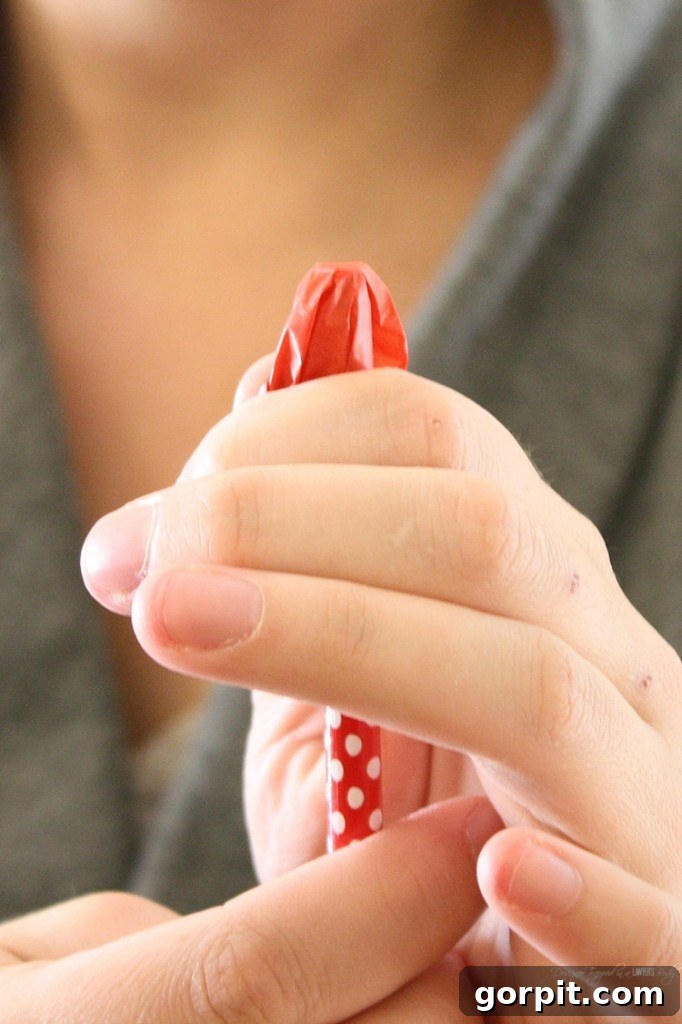 Use the eraser end of a pencil to gather each 1-inch tissue paper square, preparing it for application to the foam core board to create a fluffy texture.