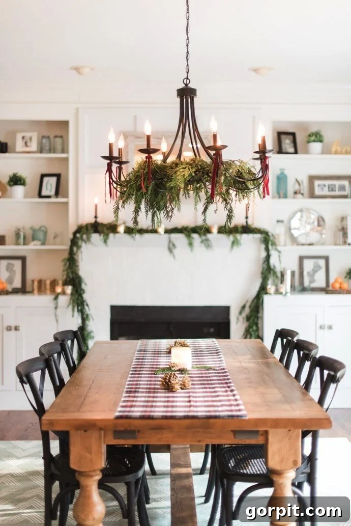 Dining room chandelier elegantly decorated for Christmas with greenery and ribbon, becoming a focal point of festive decor.