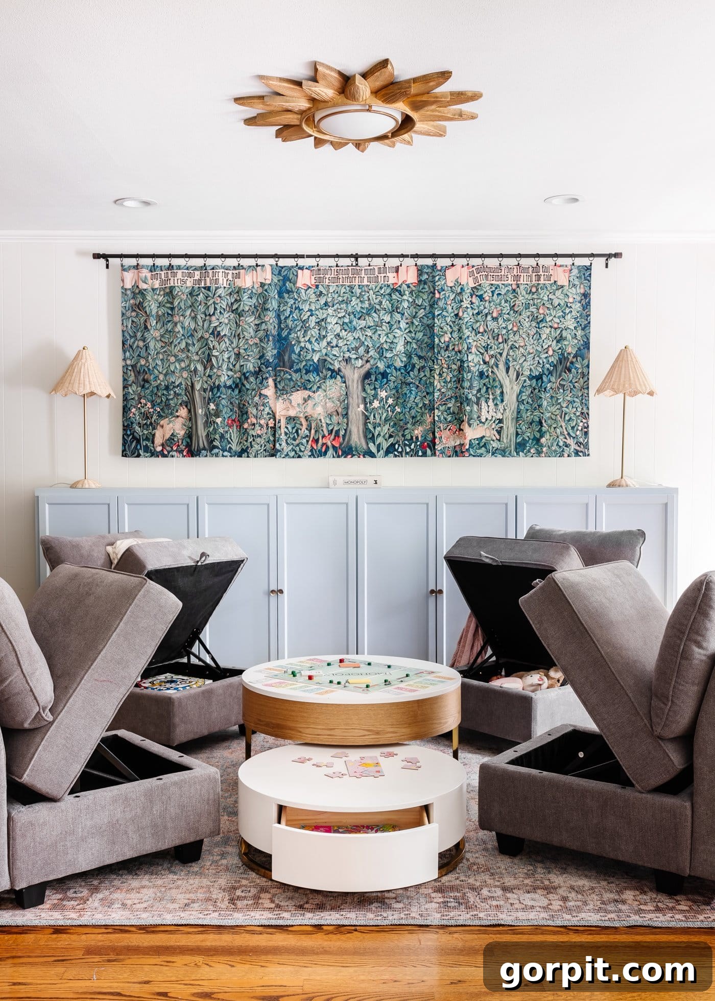 Four storage chairs with the seats lifted surround a multi-level round coffee table in a playroom. 