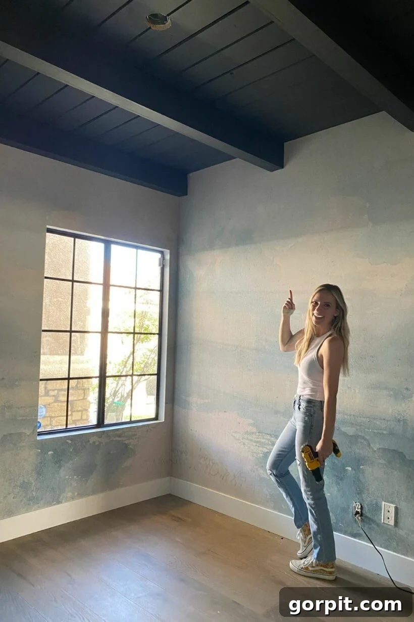 A black shiplap ceiling featuring striking DIY wood beams, creating a dramatic and rustic yet modern aesthetic in the room.